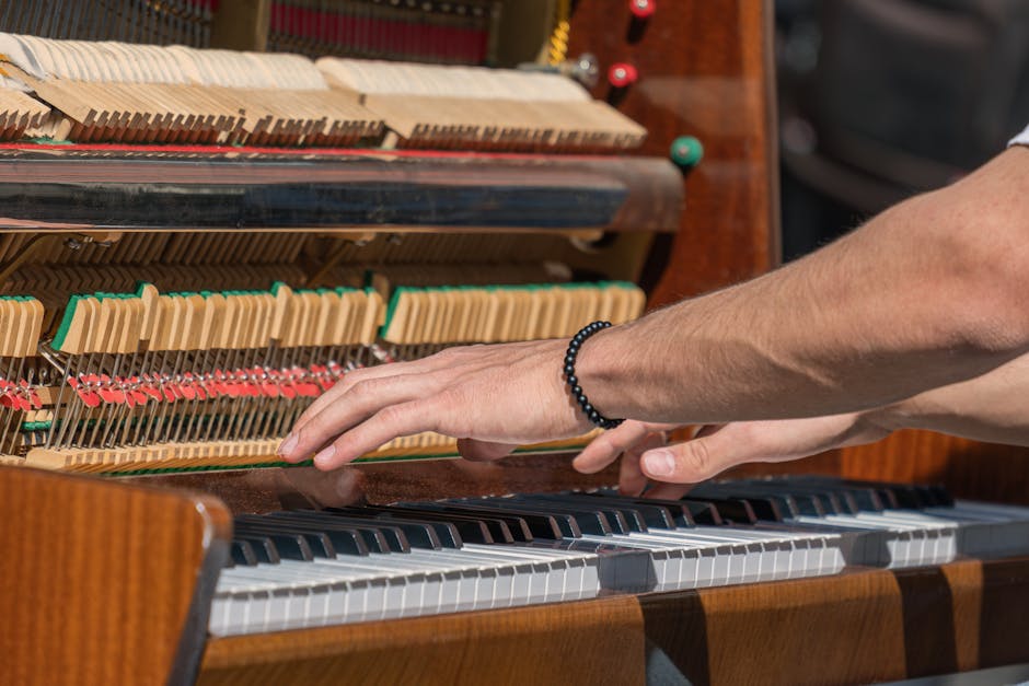 A detailed look at hands playing an upright piano with visible internal components.